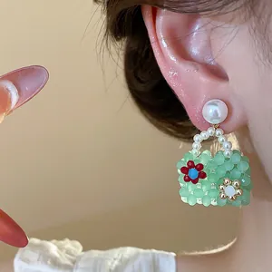 Detailed macro view of a colorful dopamine handbag-shaped pearl earring worn on a model's ear