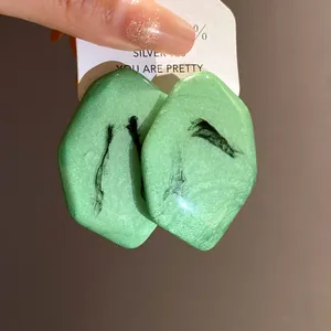 Dettaglio di eleganti orecchini in resina verde con perni in argento stile vintage
