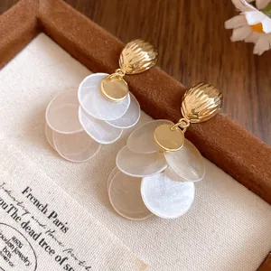 Close-up detail of luxurious 14k gold plated shell earrings with elegant white tassel