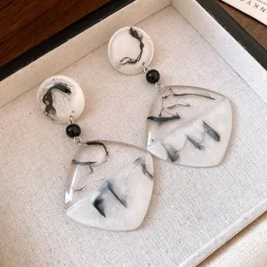 Dettaglio di orecchini pendenti in resina retrò con elegante motivo marmorizzato a inchiostro
