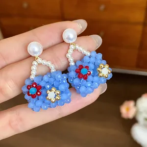 Detailed view of blue beaded handbag earrings with pearl studs and flower accents