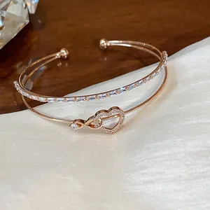 Detalle de una pulsera de dos capas en oro rosa con un corazón de circonitas brillantes.