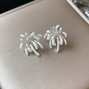 Detailed macro shot of elegant zircon firework stud earrings with white enamel drip design