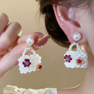 Macro detail of handmade beaded bag-shaped pearl earrings with delicate floral accents