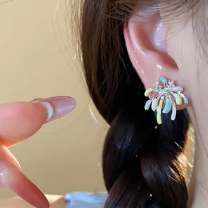Close-up view of colorful firework stud earrings with sparkling zircon on model's ear.