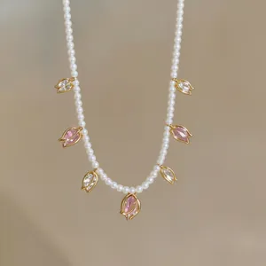 Vue détaillée d'un collier de perles élégant avec des breloques tulipes dorées et zircons