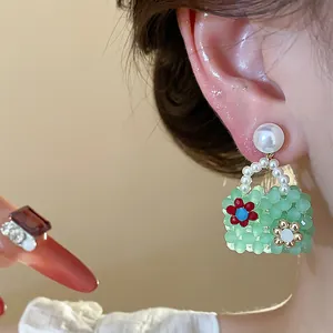 Detailed view of handmade green beaded bag earrings with pearls and flower accents.
