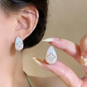 Macro shot of shimmering white teardrop earrings featuring a delicate zircon starburst motif