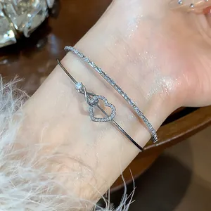 Detalle de una elegante pulsera plateada de doble capa con un corazón de circonitas