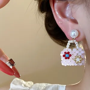 Close-up of beaded bag earring with pearl handle and floral detail
