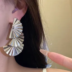 Elegant pleated fan-shaped metal dangle earrings on model for a chic style.