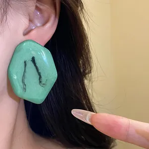 Primo piano di orecchini a perno in resina verde con effetto marmo artistico e perni in argento