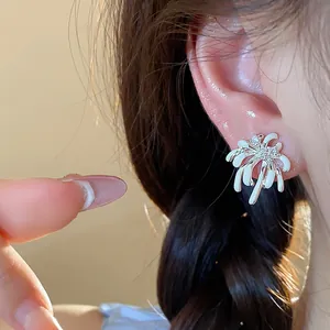 Detailed macro view of silver-tone firework earrings featuring white enamel and sparkling zircons.