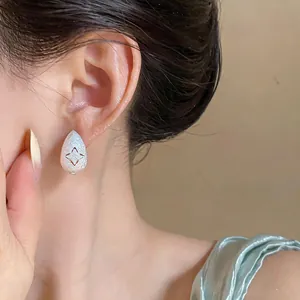 Macro view of a frosted silver teardrop earring featuring a starburst cutout design