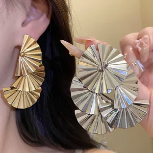 Detailed macro view showing the metallic pleated texture of fan-shaped layered drop earrings