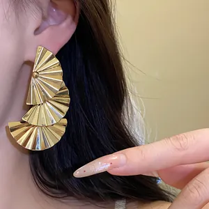 Close-up of gold fan-shaped pleated earrings with elegant metallic texture.