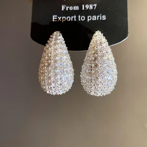 Detailed macro view of elegant water drop stud earrings paved with sparkling white zircons