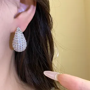 Elegant teardrop-shaped zircon stud earrings shown as detail on model's ear profile