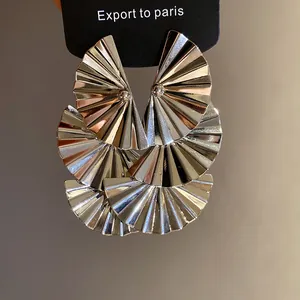 Close-up detail of elegant silver-toned metal pleated fan-shaped dangle earrings
