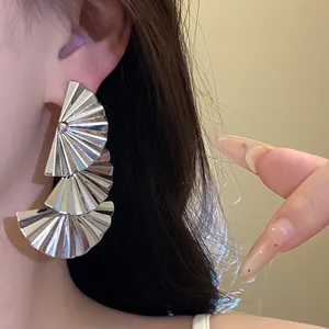 Macro shot of silver metallic pleated fan-shaped drop earrings for a chic style