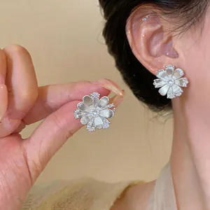Elegant silver flower stud earrings with sparkling zircons shown on model's ear