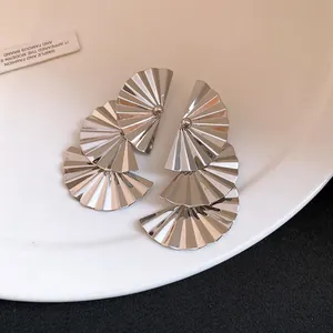 Close-up detail showing the metallic texture of silver pleated fan-shaped drop earrings.