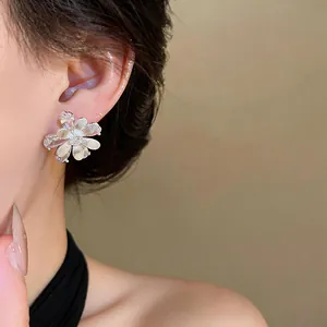 Detailed view of elegant silver flower stud earrings with sparkling zircons on model ear