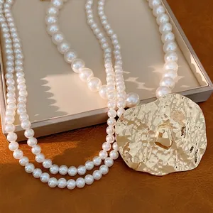 Elegant multi-layer pearl necklace with a large gold hammered metal pendant