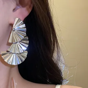 Close-up detail of stylish silver tiered pleated fan earrings with metallic finish