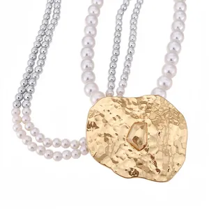 Elegant multi-strand pearl and silver bead necklace featuring a large gold hammered pendant