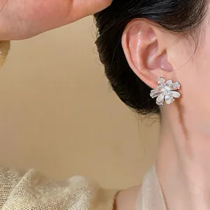 Close-up detail showing elegant silver-plated zircon flower stud earrings on an Asian model.