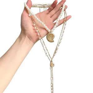 Collana di perle a strati con ciondoli a conchiglia dorati su fondo bianco