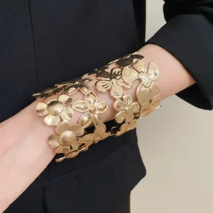 Detailansicht eines stilvollen goldenen Blumen-Armreifs aus Metall über einem schwarzen Blazer