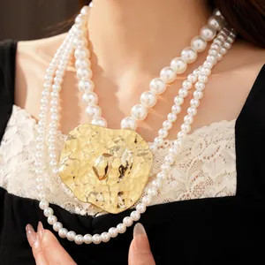 Detailed view of layered pearl necklace featuring a large hammered gold irregular pendant