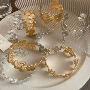 Detailansicht gold- und silberfarbener Metallarmreifen mit Blumenmuster im Vintage-Stil auf Teller