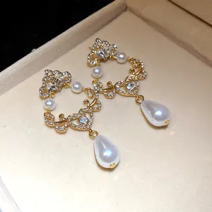 Detail view of gold filigree earrings with teardrop pearls and crystals