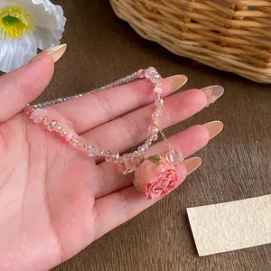Detail view of a preserved pink rose pendant on a glass beaded chain necklace