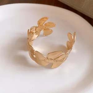 Detailansicht eines goldfarbenen, offenen Blumen-Armreifs mit Vintage-Strukturdesign.