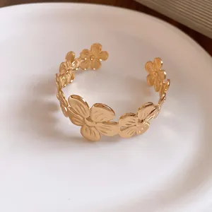 Detaillierte Nahaufnahme eines eleganten goldenen Blumen-Armreifs auf weißem Grund