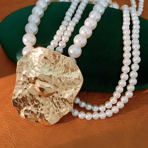 Detailed view of the hammered gold metal pendant and elegant multi-strand pearls