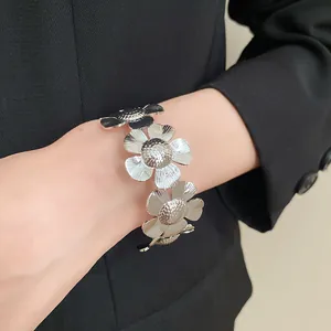 Detailaufnahme von texturierten Metallblumen an einem silbernen offenen Armreif