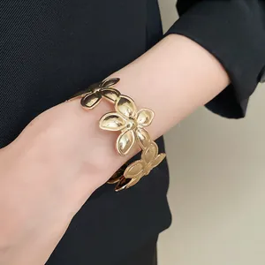 Eleganter goldener Armreif mit Blumenmuster im Vintage-Stil, getragen am Handgelenk