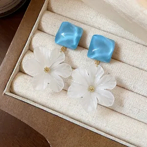 Dettaglio di petali di fiori in acrilico bianco e borchie quadrate blu in una scatola
