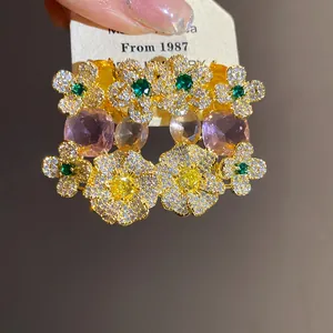 Gros plan de boucles d'oreilles fleurs en zircon avec pierres roses et fini doré