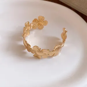 Nahaufnahme der filigranen goldfarbenen Blütenblätter und der matten Textur dieses Armreifs