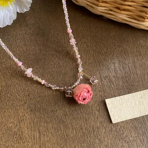 Close-up of pink preserved rose pendant on a delicate glass beaded necklace