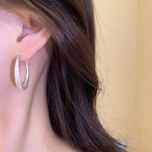 Minimalist silver needle hoop earring featuring vibrant colorful polka dots, shown on model.
