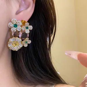 Élégantes boucles d'oreilles fleurs avec zircons et pendentifs en pierres colorées.