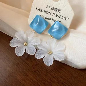 Primo piano di orecchini a fiore in acrilico con borchie quadrate blu e aghi in argento