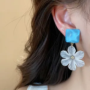 Dettaglio di eleganti orecchini a fiore in acrilico con perno quadrato blu estivo